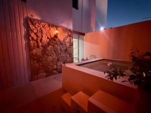 a bathroom with a tub with a stone wall at Kinara merida yucatan con alberca y jacuzzi privado in Mérida