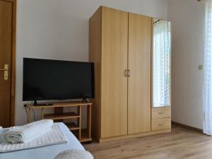 a bedroom with a television and a wooden cabinet at Apartments Mihalic in Šilo