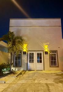 a white building with a palm tree in front of it at Kinara merida yucatan con alberca y jacuzzi privado in Mérida
