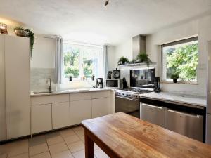 a kitchen with white cabinets and a wooden table at Le Noyer in Lierneux