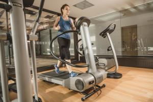 a woman running on a treadmill in a gym at Sternen Hotel Wolfurt in Bregenz