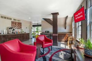 a living room with two red chairs and a kitchen at Red Roof Inn Gastonia in Gastonia