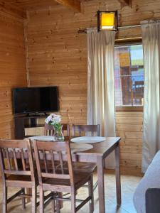 a dining room with a table and chairs and a television at Domki Marlin in Rewal