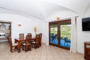 a dining room with a table and chairs and a television at Porto Cervo-Villa La Gjanda in Abbiadori