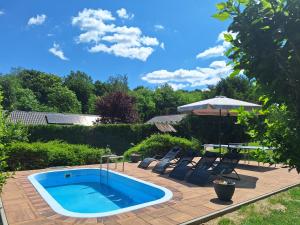 a swimming pool in a yard with chairs and an umbrella at Boglárka Vendégház in Vasvár