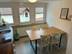 a kitchen with a wooden table and chairs and two windows at Hauckwald Apartment 1 in Alzenau