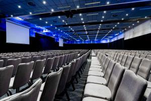 an empty auditorium with chairs and a screen at NH Noordwijk Conference Centre Leeuwenhorst in Noordwijkerhout