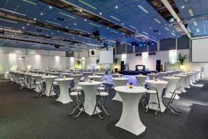 a large room with white tables and chairs at NH Noordwijk Conference Centre Leeuwenhorst in Noordwijkerhout