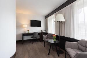 a living room with a couch and a desk and a tv at NH Noordwijk Conference Centre Leeuwenhorst in Noordwijkerhout