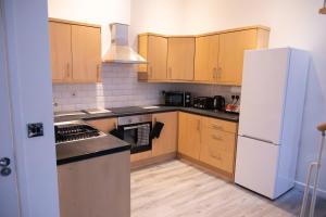 a kitchen with wooden cabinets and a white refrigerator at Luton Grove in Liverpool