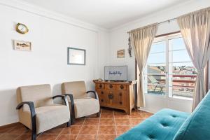 a living room with two chairs and a tv and a window at Salt & Sand Costa Nova Beach in Costa Nova