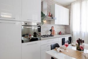 a kitchen with white cabinets and a table with wine glasses at Brezza della Fortuna in Fano