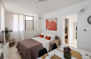 a white bedroom with a bed and a table with chairs at Brezza della Fortuna in Fano