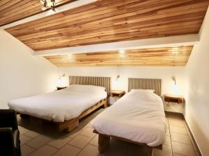 two beds in a room with wooden ceilings at Le Noyer in Lierneux