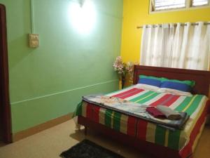 a bedroom with a bed with colorful sheets and a window at niribili homestay in Dibrugarh