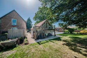 a house with a deck next to a brick building at The TreeHouse Hideaway in Shrewsbury