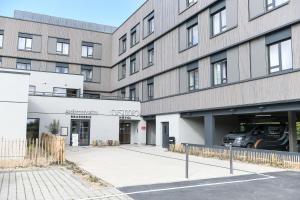 a parking lot in front of a building at The Originals Boutique, Osmo Hôtel, Rennes Sud Chantepie in Chantepie