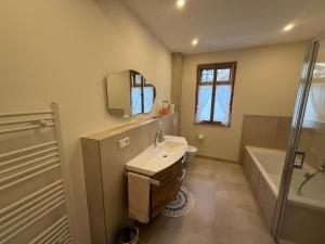 a bathroom with a sink and a tub and a mirror at Wohnen im Denkmal in Weilrod