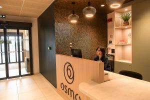 a woman sitting at a desk in an office at The Originals Boutique, Osmo Hôtel, Rennes Sud Chantepie in Chantepie