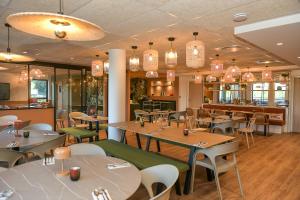 a restaurant with tables and chairs and a bar at The Originals Boutique, Osmo Hôtel, Rennes Sud Chantepie in Chantepie