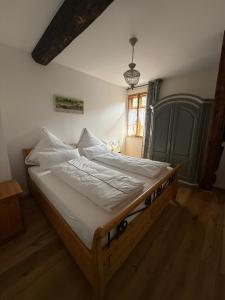 a bedroom with a bed with white sheets and a window at Wohnen im Denkmal in Weilrod