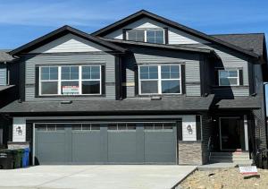 a house with two garage doors in front of it at La Rose des Prairies -The Prairie Rose in Calgary