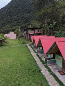 a row of houses with red roofs in a field at Pablito Hostel Challhuay in Colcapampa