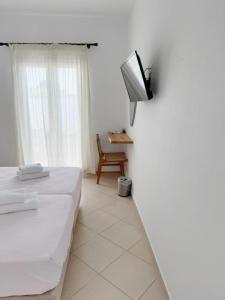 a room with two beds and a tv on a wall at Argo Rooms Antiparos in Antiparos