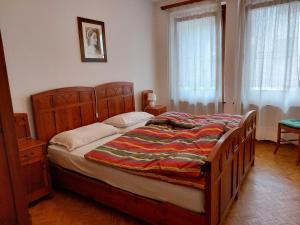 ein Schlafzimmer mit einem Bett mit Holzrahmen und Fenstern in der Unterkunft CasaColdai in Alleghe