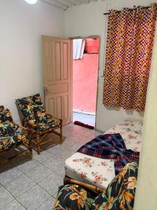 a bedroom with a bed and a chair and a window at Casa a 3 minutos da basilica in Aparecida