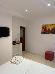 a white room with a bed and a painting on the wall at Luciano Rooms in Ksamil