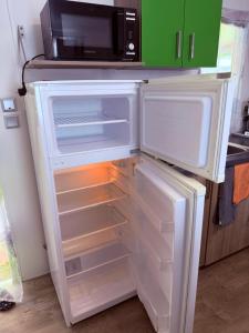 an open refrigerator with a microwave on top of it at Mobilheim Chalet bei Georg in Seekirchen am Wallersee