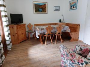 ein Wohnzimmer mit Tisch, Stühlen und Fernseher in der Unterkunft CasaColdai in Alleghe