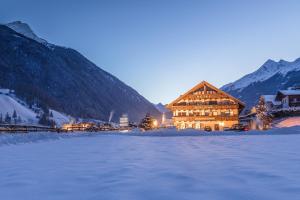 a large building in the snow in front of a mountain at B&B Hotel Bergjuwel in Neustift im Stubaital