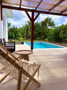 a patio with a table and chairs and a pool at Villa neuve Casa Helena - Piscine privée et jardin - 6 pers - Saint-Esprit - Sud Martinique in Quartier Palmène