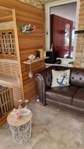 a living room with a brown leather couch and a table at Hillside Olive Apartmanház közös WELLNESsell in Pécs +12 photos