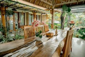a long wooden table in a room with plants at Green Bali Guest House in Munggu