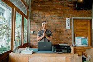 a man standing in front of a desk with a laptop at Green Bali Guest House in Munggu