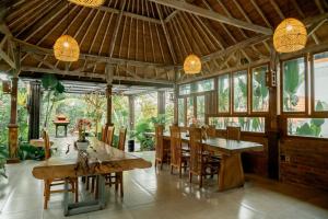 a dining room with wooden tables and chairs at Green Bali Guest House in Munggu