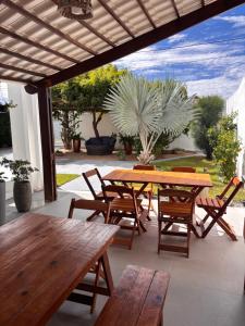 a patio with wooden tables and chairs and the ocean at Casa Blanca in Galinhos