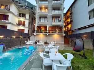a hotel patio with tables and chairs and a swimming pool at Hotel Asiia Holiday with Swimming Pool -Central Heated and Air Cooled, Near mall road in Kasol