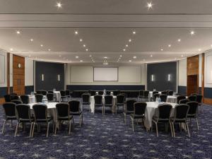 a conference room with tables and chairs and a projection screen at Sofitel London Gatwick in Horley