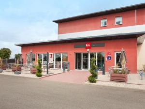 a red building with benches in front of it at ibis Albert Pays de Somme in Albert