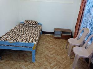 a bedroom with a bed and two chairs and a table at Serene Lodge in Shillong +1 photo
