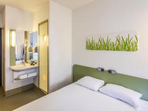 a bedroom with a bed and a bathroom with a sink at ibis budget Antwerpen Centraal Station in Antwerp