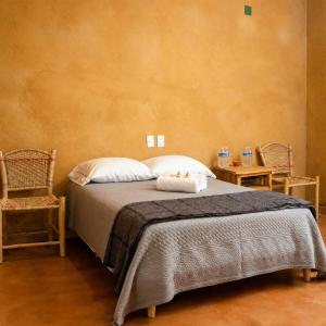 a bedroom with a bed with two pillows and two chairs at Ixak Cabañas in La Pimienta