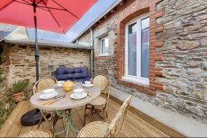 a table with chairs and an umbrella on a patio at Maison Ty Bihan Sioul in Sarzeau