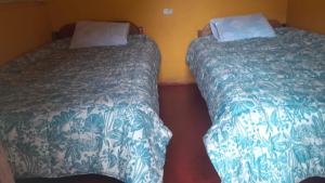 two beds sitting next to each other in a room at Pablito Hostel Challhuay in Colcapampa