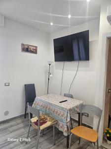 a dining room with a table with chairs and a flat screen tv at Fortuna in Diano Marina