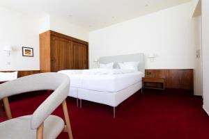 a bedroom with a white bed and a red carpet at Romantik Hotel zur Sonne in Badenweiler +51 photos
